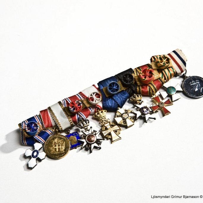 Næla með tíu orðum og peningum, talið frá vinstri:

1 Riddarakross hinnar íslensku fálkaorðu.

Forseti Íslands sæmdi borgarstjóra Bjarna Benediktsson riddarakrossi hinnar

íslensku fálkaorðu 18. ágúst 1946.

Forseti Íslands sæmdi dómsmálaráðherra Bjarna Benediktsson fyrrverandi

utanríkisráðherra stórkrossi hinnar íslensku fálkaorðu 1. desember 1953.

2 Lýðveldishátíðarmerkið. Lýðveldi endurreist á Íslandi 17. júní 1944.

Forseti Íslands sæmdi Bjarna Benediktsson lýðveldishátíðarmerkinu 8. júlí 1944.

3 Heiðurspeningur sem gefin var út til minningar um vígslu og afhendingu Skálholtsstaðar

til Þjóðkirkjunnar 21. júlí 1963.

Forseti Íslands sæmdi dóms- og kirkjumálaráðherra Bjarna Benediktsson

heiðurspeningnum 21. júlí 1963.

4 St.Olavs Orden.

Håkon Noregskonungur sæmdi Bjarna Benediktsson stórkrossi hinnar konunglegu

St.Olavs Orden 21. júlí 1947.

5 Dannebrogorden.

Ridder af 1. grad af Dannebrogorden, Danmörk.

6 The Order of the White Rose of Finland

Juho Kusti Paasikivi forseti Finnlands sæmdi Bjarna Benediktsson The Order of the

White Rose, stórkrossinum, 20 ágúst 1948.

7 The Order of the Polar Star.

Gustaf VI Adolf Svíakonungur sæmdi Bjarna Benediktsson stórkrossi hinnar

sænsku Norðstjörnu, Polar Star, 4. janúar 1966.

8 Verdienstorden der Bundesrepublik Deutschland.

Das Großkreuz mit Stern, Þýskaland. Bjarni Benediktsson hefur líklega verið

sæmdur orðunni í kringum 1955 (sjá einnig öskju 8-4).

9 Order of the Oak Crown.

Cross of a Knight in the Order of the Oak Crown, Lúxemborg. Bjarni Benediktsson

var líklega sæmdur orðunni 27. ágúst 1969.

10 The King´s Medal for Service in the Cause of Freedom.

Líklega hefur Bjarni Benediktsson fengið þessa bresku orðu á eftirstríðsárunum.