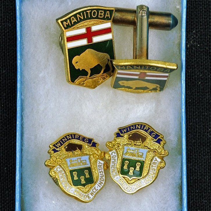 Á tveim barmmerkjum stendur WINNIPEG COMMERCE PRUDENCE INDUSTRY. Á einu barmmerki er mynd af Buffalo ogstendur MANITOBA. Á ermahnappinum stendur MANITOBA.