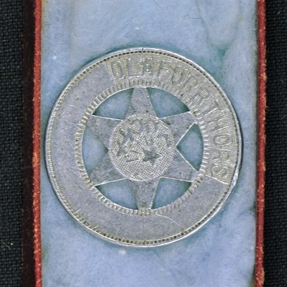 Askja með hring og stjörnu.

Á hringnum stendur: ÓLAFUR THORS og á stjörnunni stendur: LUCKY

Á bakhlið stendur meðal annars: HARVARD, JAMESTOWN, N. Y.