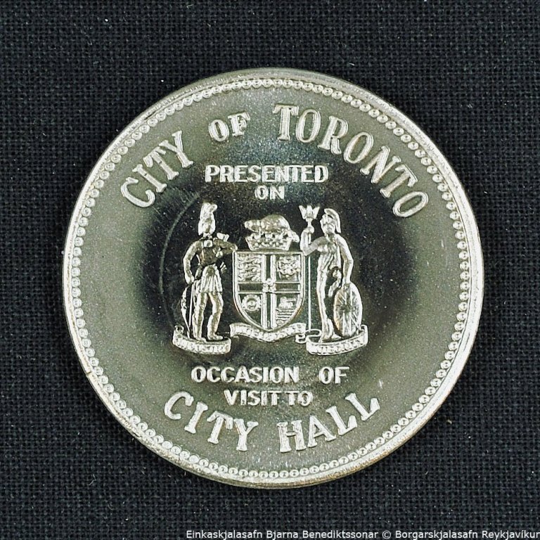 Peningur. Á framhlið peningsins stendur: CITY OF TORONTO. PRESENTED ON OCCASION OF VISIT TO CITY HALL. Á bakhlið peningsins stendur: CITY HALL TORONTO ONTARIO CANADA.