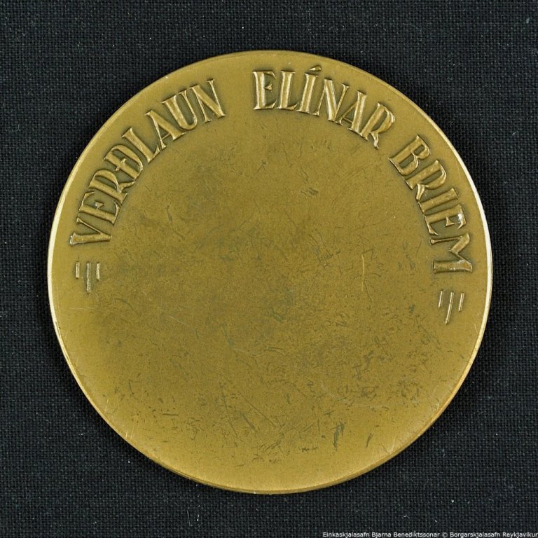 Peningur. Á framhlið peningsins stendur: ALDREI VAR ÞARFARA STÓRVIRKI GERT EN GETA SITT MANNFÉLAG MANNAÐ. Á bakhlið peningsins stendur: VERÐLAUN ELÍNAR BRIEM.