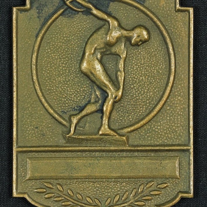 Merki. Á framhlið merkisins stendur: XIV OLYMPIAD LONDON 1948. Á bakhlið er mynd af ólympíukeppanda.