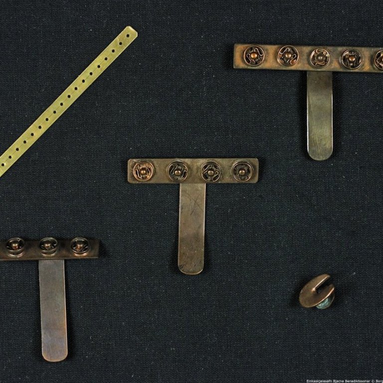 Askja.

Í henni eru þrjár nælur með smellum fyrir merki, lítil járnstöng með götum og næla

fyrir barmmerki.