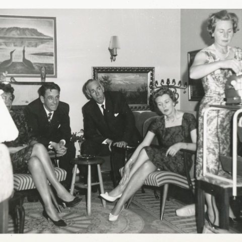 Veisla hjá Hólmfríði og Hans. Sigríður McKenzie (f. 1917 - d. 2003) , systir Hólmfríðar og Kristjáns, notar sýningarvél. Talið frá vinstri Aldís Brynjólfsdóttir Schram (1917-1991), óþekktur, Björgvin Schram (1912-2001), óþekkt.Borgarskjalasafn Reykjavíkur