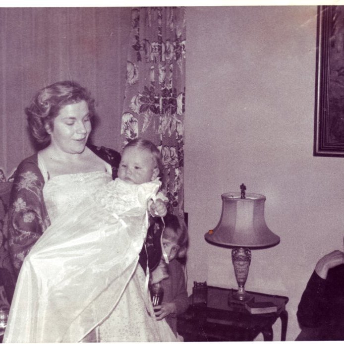 1961. Margrét Thors heldur á Ólafi Tryggvasyni á skírnardaginn í stofunni á Garðastræti 41. Afi barnsin, Snæbjörn Jónsson bóksali fylgist með.