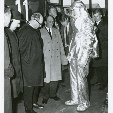 Heimsókn til slökkviliðsins á Keflavíkurflugvelli í maí árið 1967. Á myndinni sést slökkviliðsmaður í hlífðarbúningi (eldföstum búningi). Meyvant Sigurðsson er fjórði f.v. á myndinni. Axel Guðmundsson (1905-1971) er þriðji frá vinstri. Borgarskjalasafn Re