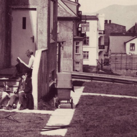 Húsinu fylgdi stór lóð og þar lét Ingibjörg strax til sín taka við garð- og trjárækt. Börnin voru ekki jafnhrifin þegar kom að því að tína 200 lítra af rifsberjum á haustin. Mynd: Morgunstund  við bakdyrnar á Garðastræti 41 vorið 1930: Gamli maðurinn er Indriði Einarsson sem bjó við Tjarnargötu og kom gjarnan í morgunkaffi til dóttur sinnar. Stúlkan með bókina er Marta og Thor bróðir hennar vökvar garðinn.